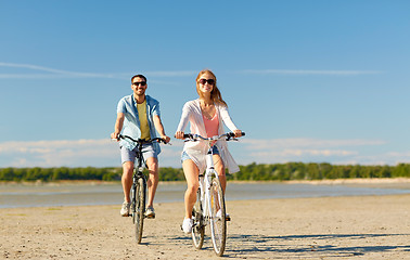 Image showing happy young couple riding bicycles at seaside