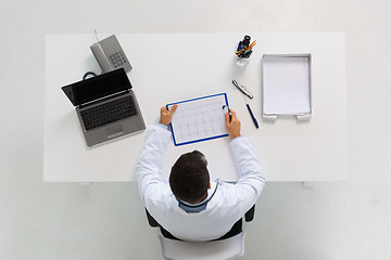 Image showing doctor with cardiogram and laptop at clinic