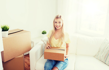 Image showing smiling young woman with cardboard box at home