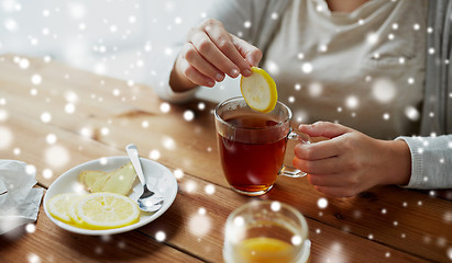 Image showing close up of ill woman adding lemon to tea cup