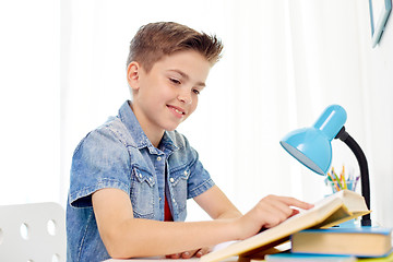 Image showing student boy reading book at home table