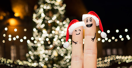 Image showing two fingers in santa hats over christmas tree