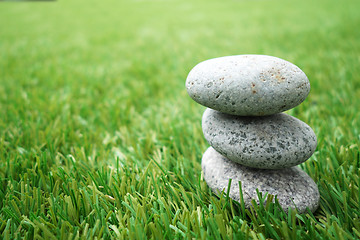 Image showing Pebbles stacked up on grass