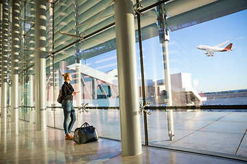 Image showing Young woman waiting at airport, looking through the gate window.