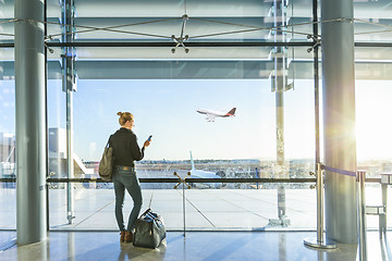 Image showing Young woman waiting at airport, looking through the gate window.