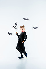 Image showing Little girl witch in black dress over magical accessories. Halloween, the studio evening.