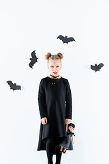 Image showing Little girl witch in black dress over magical accessories. Halloween, the studio evening.