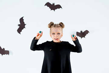 Image showing Little girl witch in black dress over magical accessories. Halloween, the studio evening.