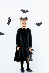 Image showing Little girl witch in black dress over magical accessories. Halloween, the studio evening.