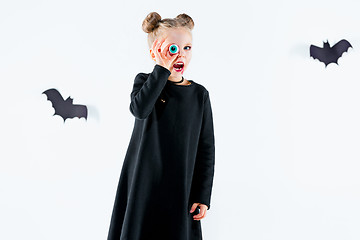 Image showing Little girl witch in black dress over magical accessories. Halloween, the studio evening.