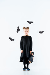 Image showing Little girl witch in black dress over magical accessories. Halloween, the studio evening.