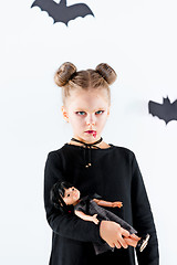 Image showing Little girl witch in black dress over magical accessories. Halloween, the studio evening.