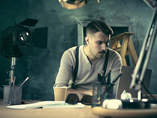 Image showing Portrait of a bearded businessman who is checking details of his upcoming meeting in his notebook and typing.