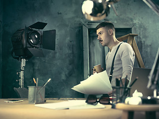 Image showing Portrait of a bearded businessman who is checking details of his upcoming meeting in his notebook and typing.