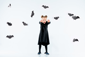 Image showing Little girl witch in black dress over magical accessories. Halloween, the studio evening.