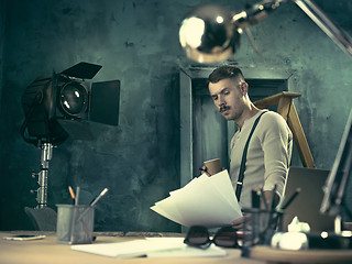 Image showing Portrait of a bearded businessman who is checking details of his upcoming meeting in his notebook and typing.