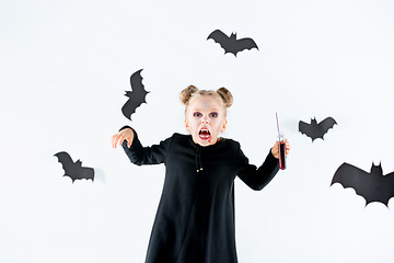 Image showing Little girl witch in black dress over magical accessories. Halloween, the studio evening.