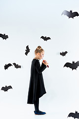 Image showing Little girl witch in black dress over magical accessories. Halloween, the studio evening.