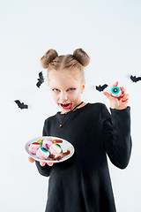 Image showing Little girl witch in black dress over magical accessories. Halloween, the studio evening.