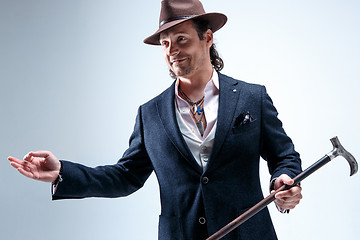 Image showing The mature man in a suit and hat holding cane.