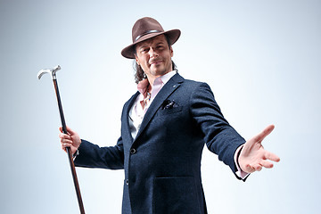 Image showing The mature man in a suit and hat holding cane.