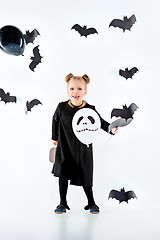 Image showing Little girl witch in black dress over magical accessories. Halloween, the studio evening.