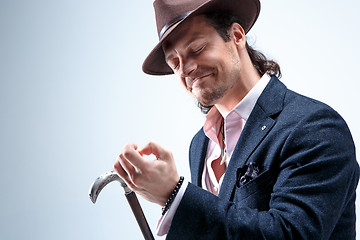 Image showing The mature man in a suit and hat holding cane.