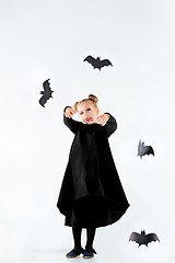 Image showing Little girl witch in black dress over magical accessories. Halloween, the studio evening.