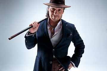 Image showing The mature man in a suit and hat holding cane.