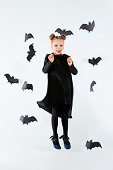 Image showing Little girl witch in black dress over magical accessories. Halloween, the studio evening.