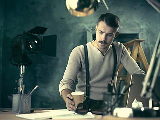 Image showing Portrait of a bearded businessman who is checking details of his upcoming meeting in his notebook and typing.