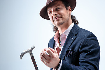 Image showing The mature man in a suit and hat holding cane.