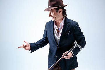 Image showing The mature man in a suit and hat holding cane.