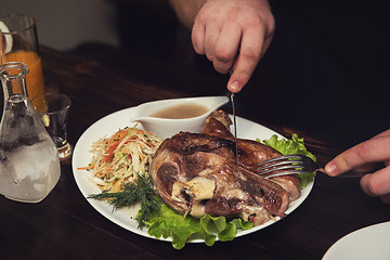 Image showing Man eats tasty dish of pork shank