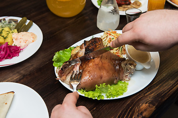 Image showing Man eats tasty dish of pork shank