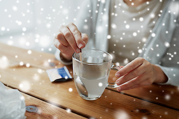 Image showing ill woman stirring medication in cup with spoon