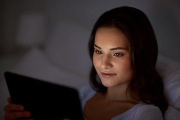 Image showing young woman with tablet pc in bed at home bedroom