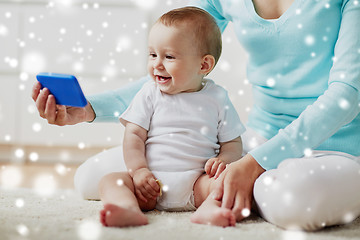 Image showing happy mother showing smartphone to baby at home