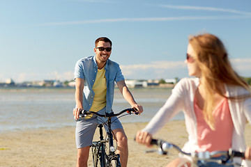 Image showing happy young couple riding bicycles at seaside