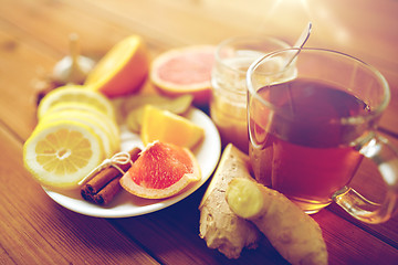 Image showing ginger tea with honey, citrus and cinnamon on wood