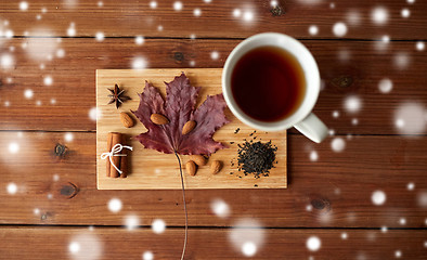 Image showing cup of tea, maple leaf and almond on wooden board