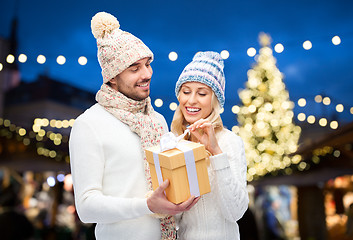 Image showing happy couple with gift box over christmas lights