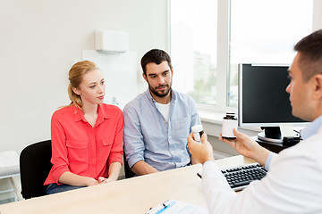 Image showing doctor showing medicine to family couple at clinic