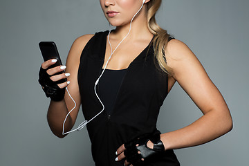Image showing sportswoman with smartphone and earphones