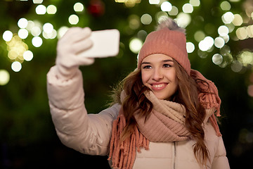 Image showing young woman taking selfie over christmas tree