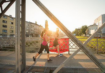 Image showing young couple jogging across the bridge in the city