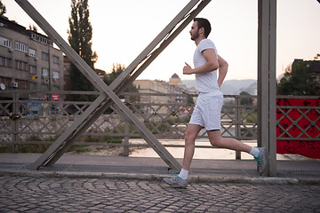 Image showing man jogging across the bridge at sunny morning