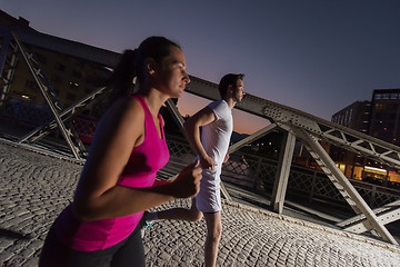 Image showing couple jogging across the bridge in the city