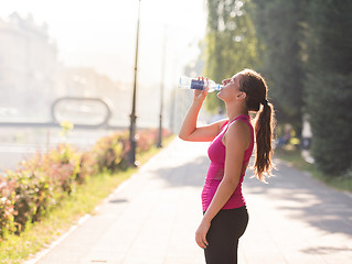 Image showing woman drinking water from a bottle after jogging