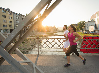 Image showing young couple jogging across the bridge in the city